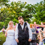 Guests throw confetti at a couple as they walk down the aisle at their Wisconsin backyard wedding.