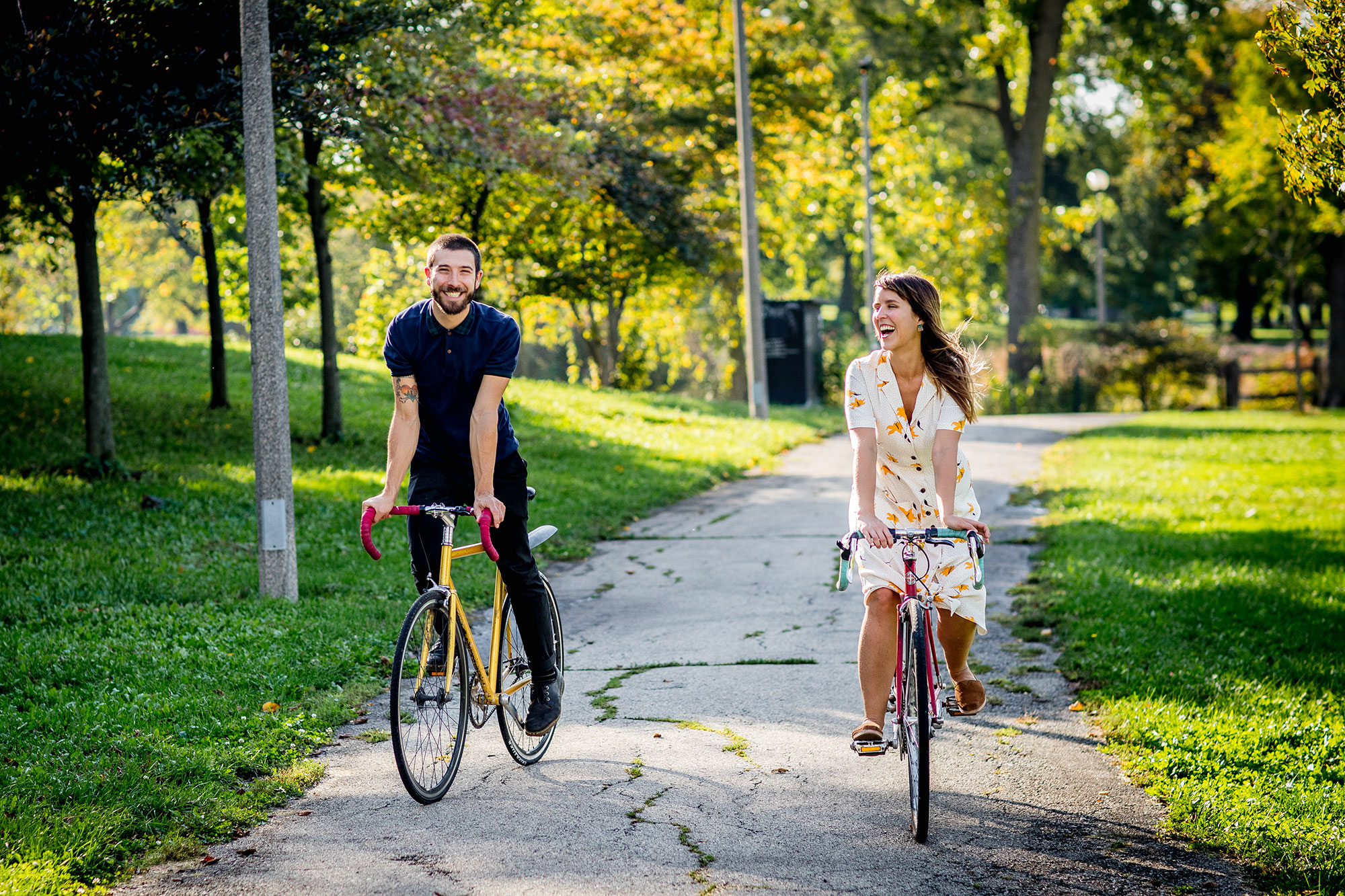 A couple laughs together while riding bikes during their Humboldt Park engagement session in Chicago.