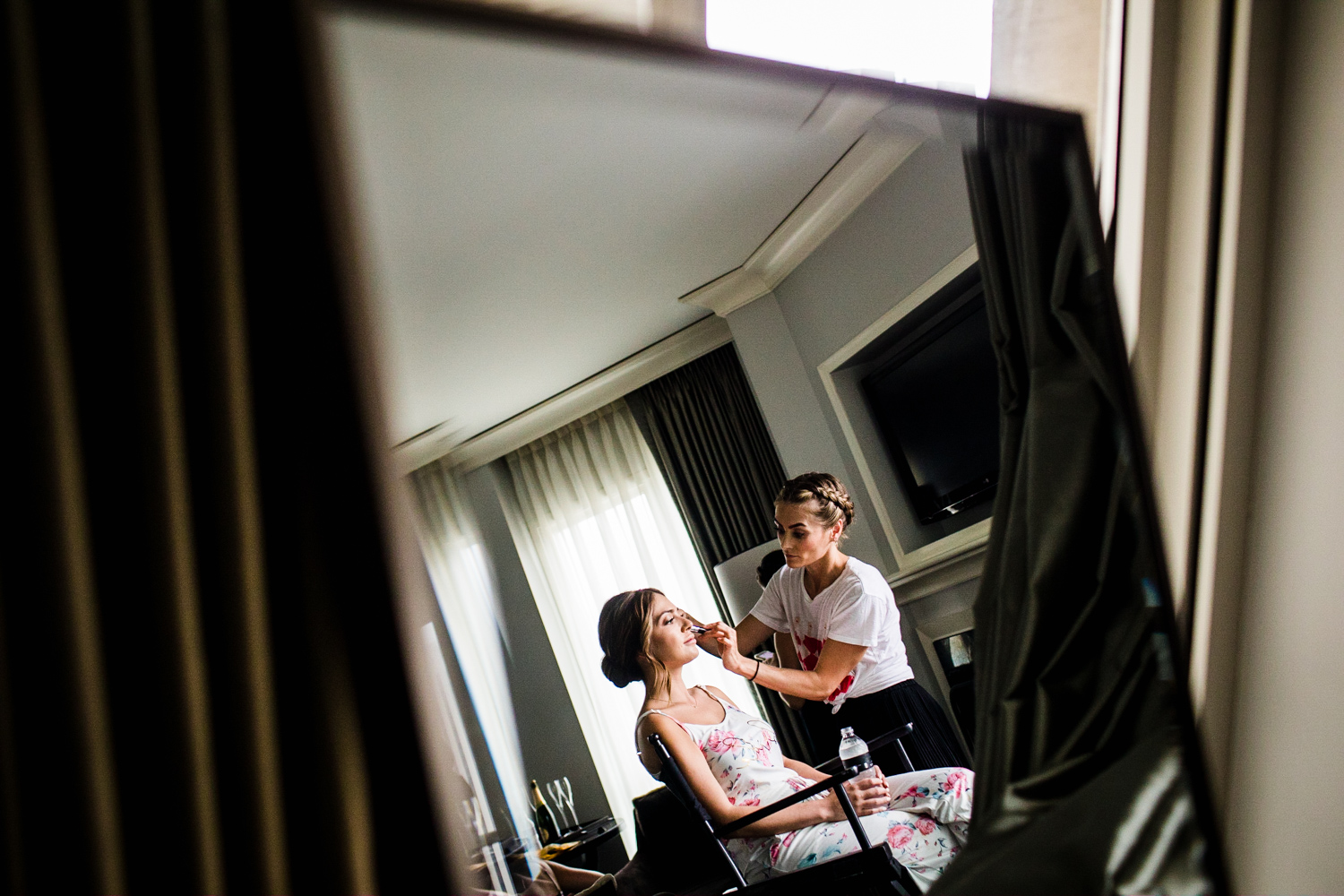 A bride is reflected in a mirror while getting her makeup done before her Gallery Marchetti wedding.