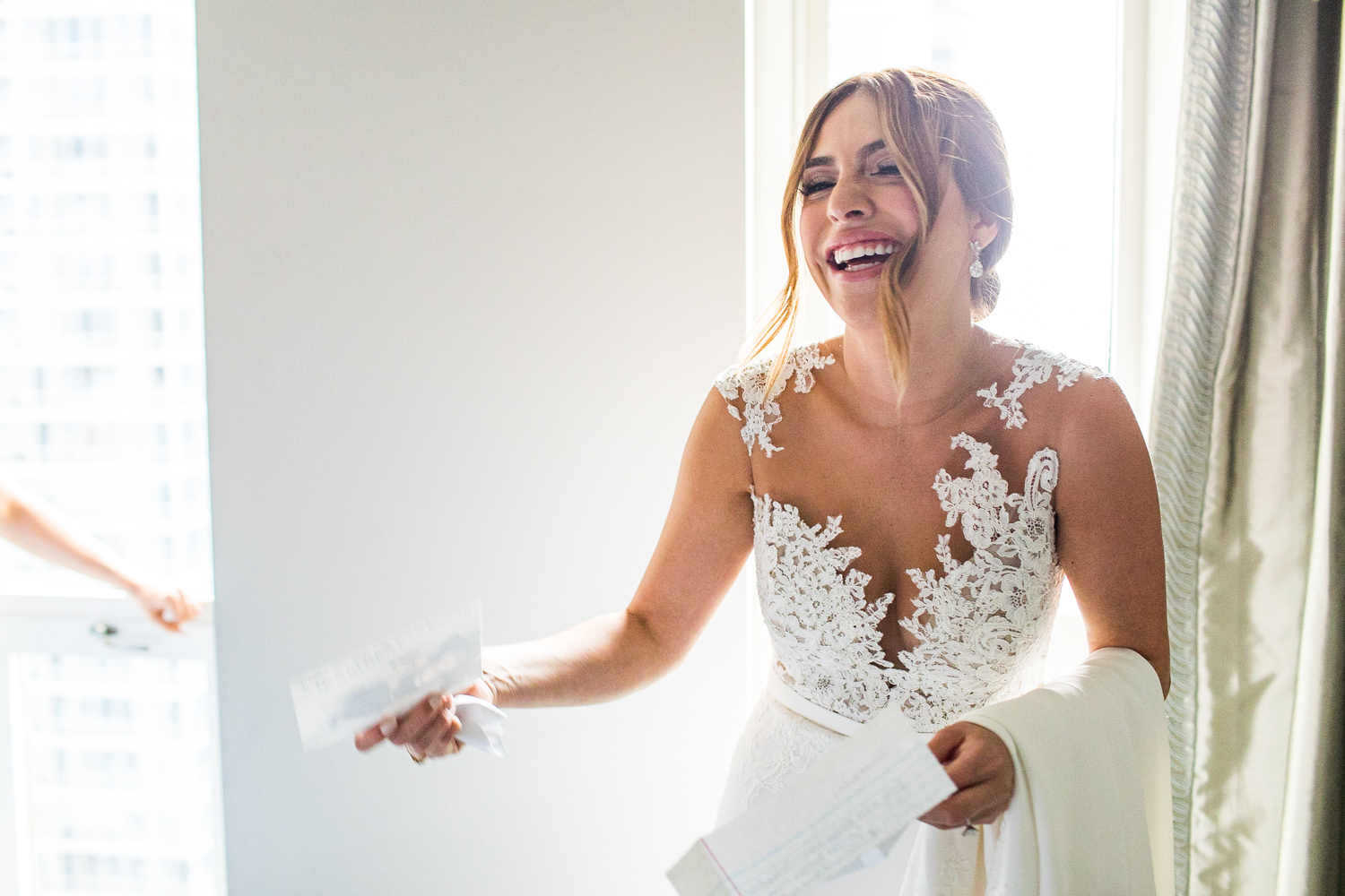 A bride laughs after reading a letter from her family before a Gallery Marchetti wedding.