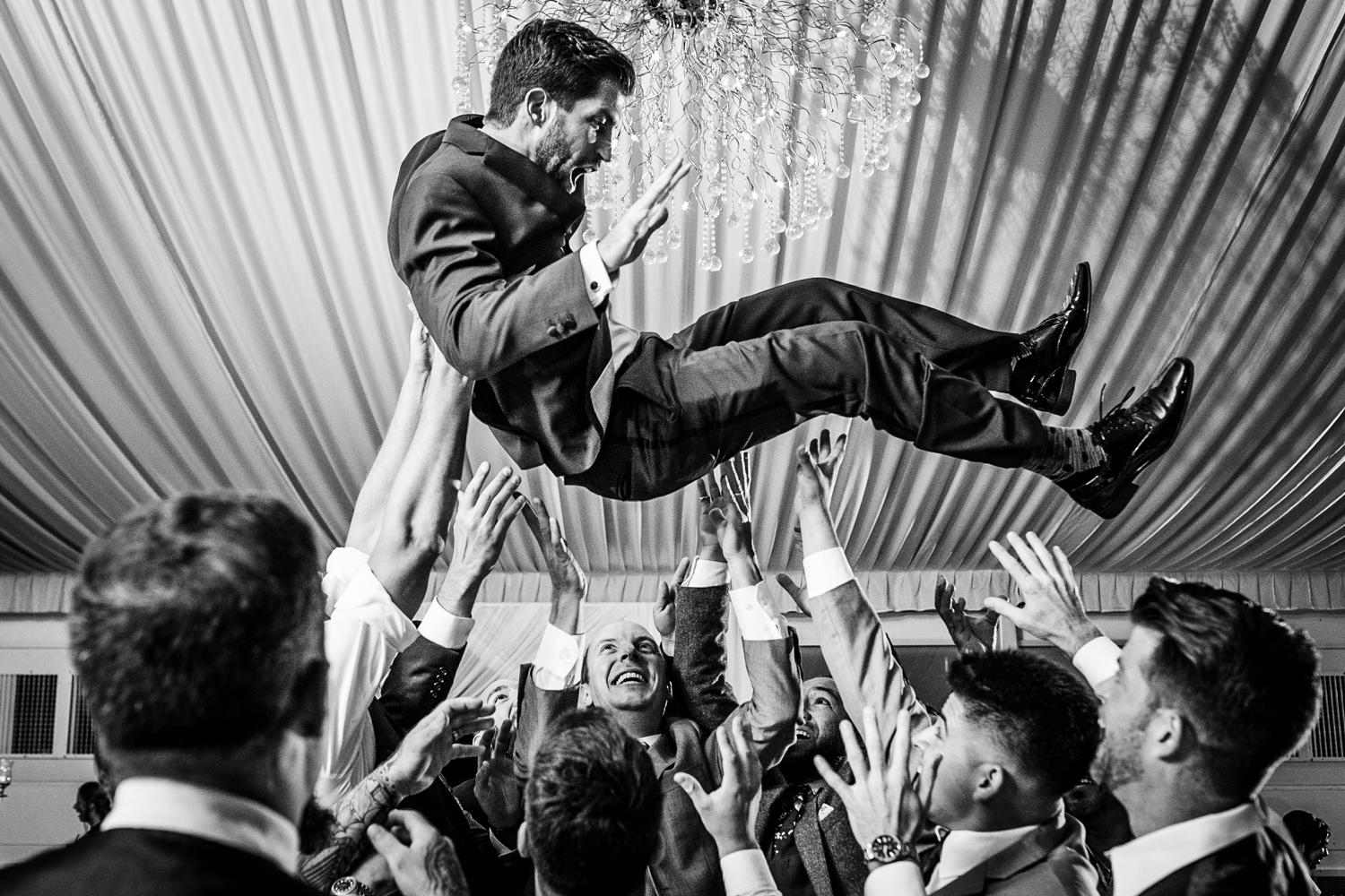 Guests throw the groom into the air at a Gallery Marchetti wedding.