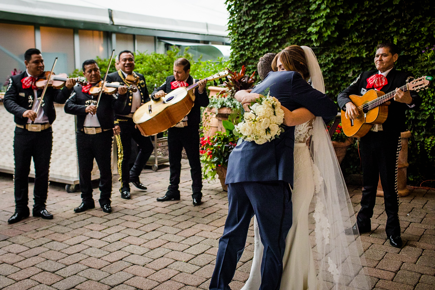A bride and groom share a hug as a mariachi band plays during a Gallery Marchetti wedding.