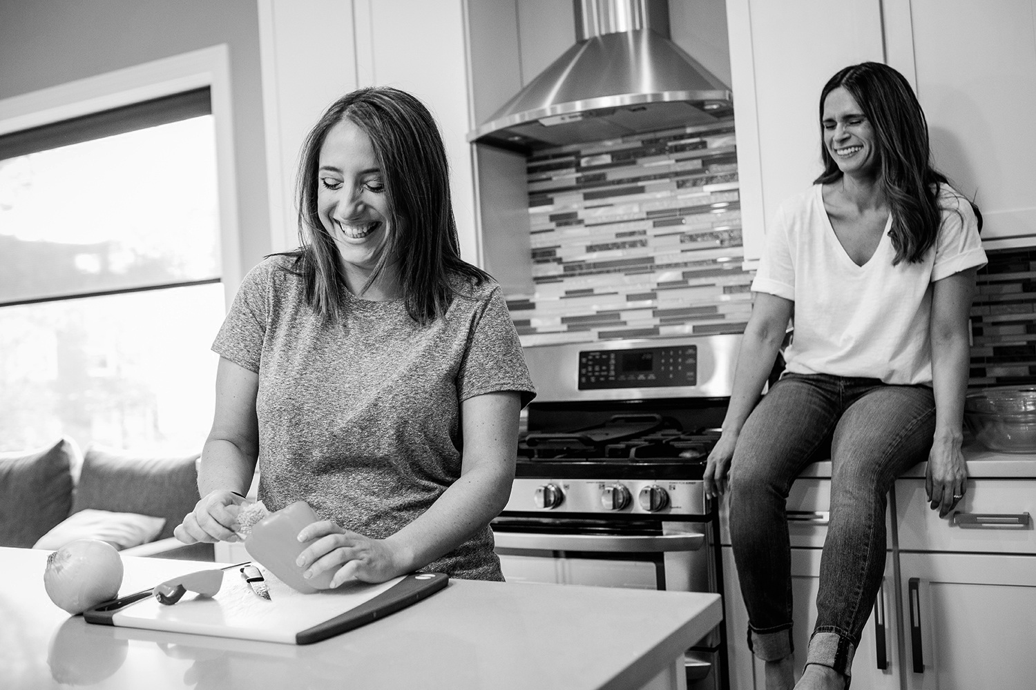 A couple laughs together while making dinner during their Andersonville engagement session.