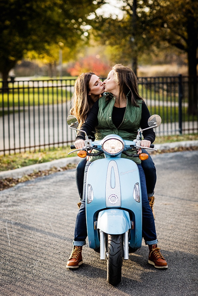 A couple kisses on a Vespa during an Andersonville engagement session.