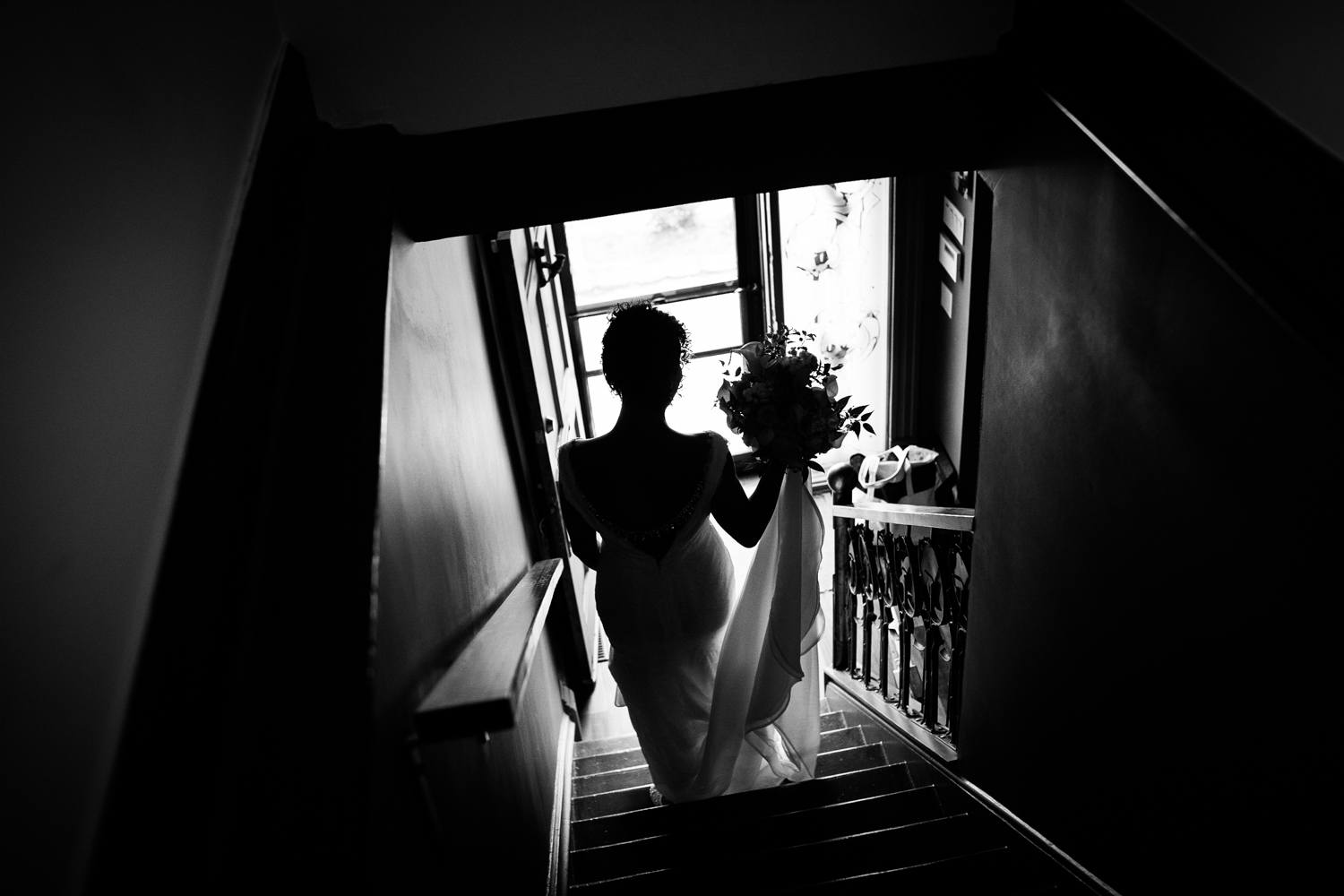 A bride in silhouette walking down the stairs before her Garfield Park Conservatory wedding.