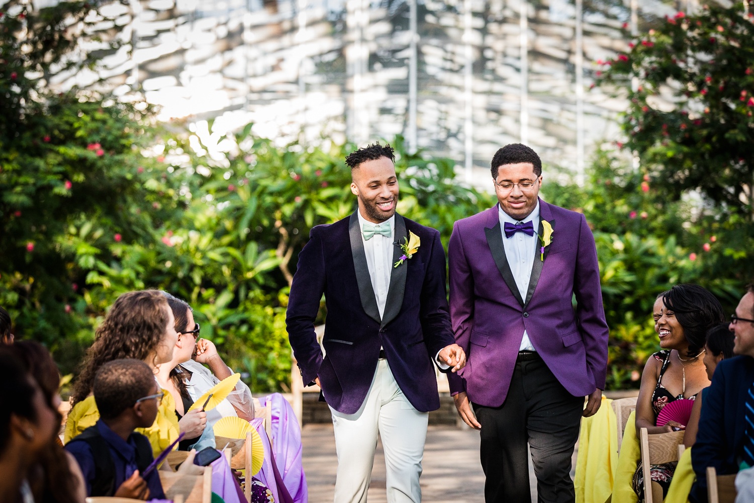 A groom walks down the aisle with his brother during a Garfield Park Conservatory wedding.