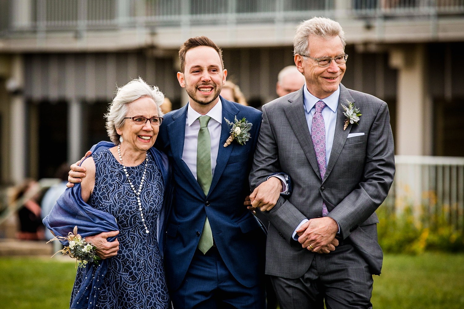 A groom walks down the aisle with his parents at an Illinois Beach Resort wedding