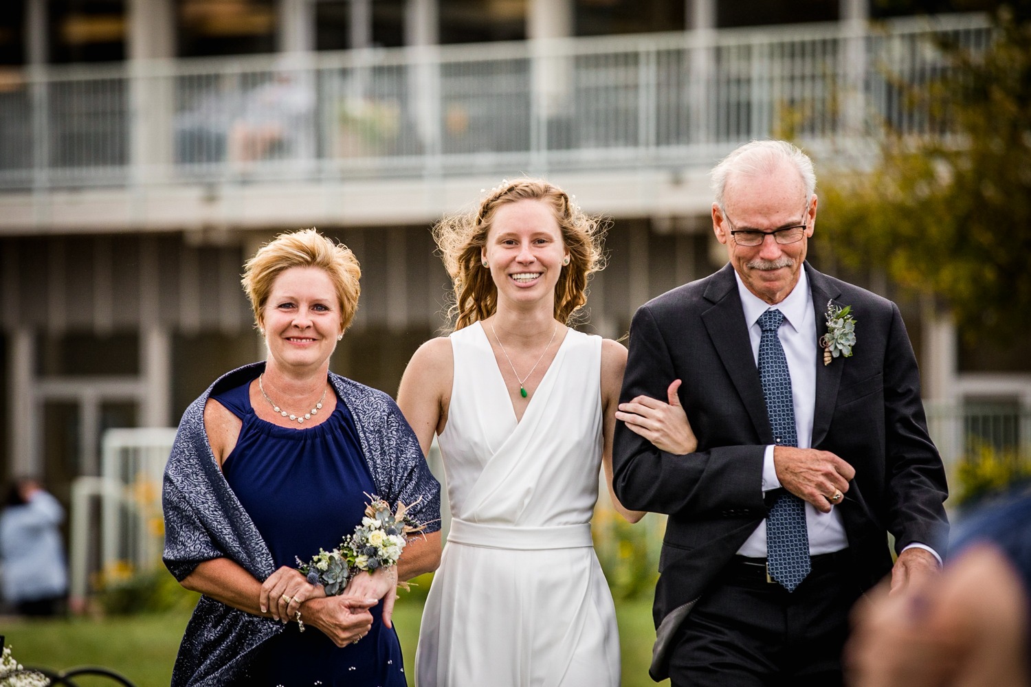 A bride walks down the aisle with her parents at an Illinois Beach Resort wedding