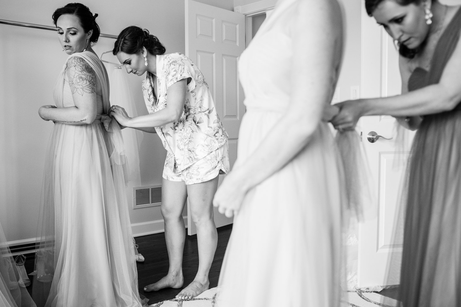 Bridesmaids help each other get ready at home