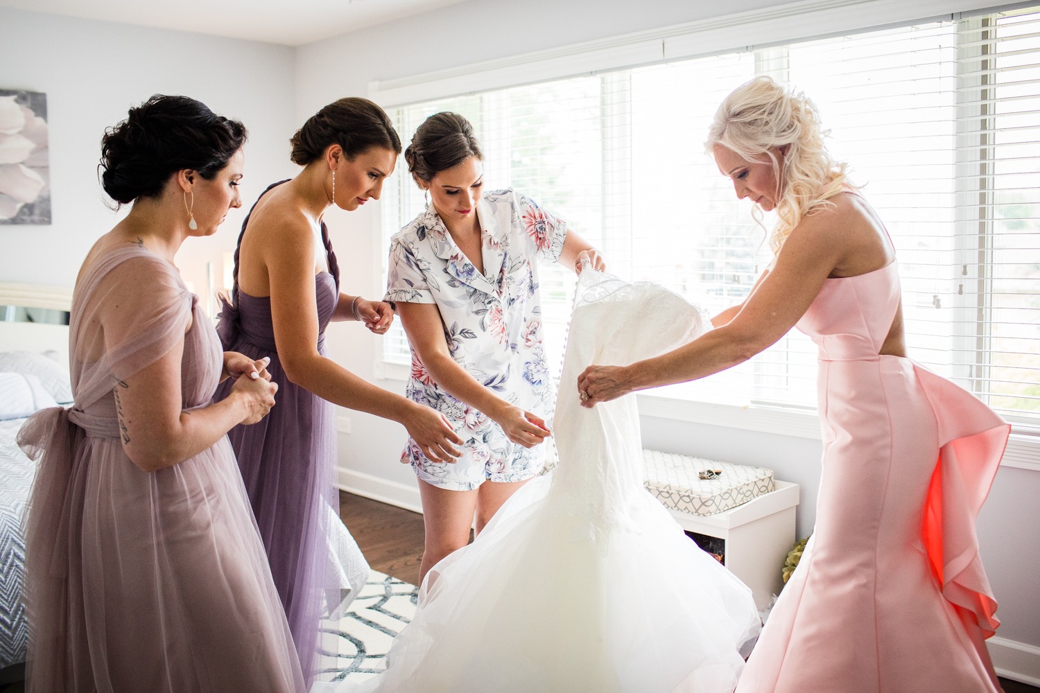 A bride and her wedding party help her put on her dress before a Glen Club wedding. 