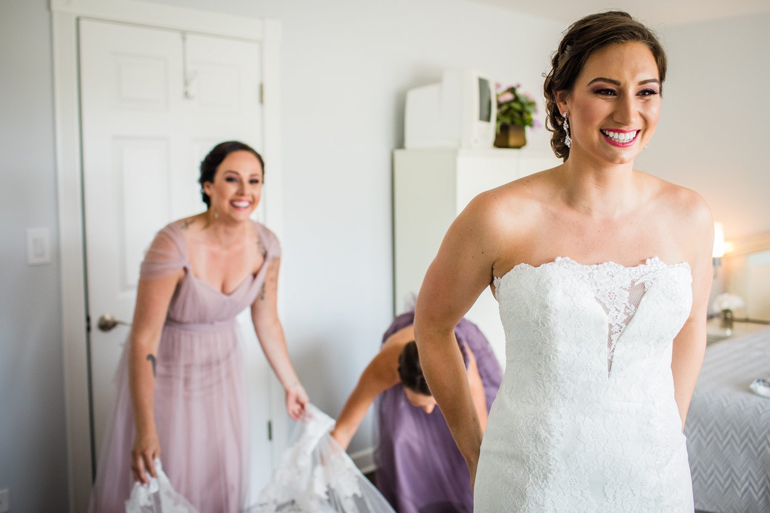 A bride laughs while getting ready at her home. 