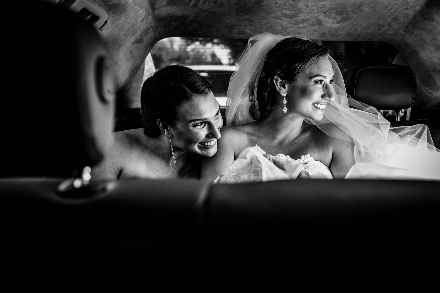 A bride and her sister look out of a limo window before her wedding ceremony. 