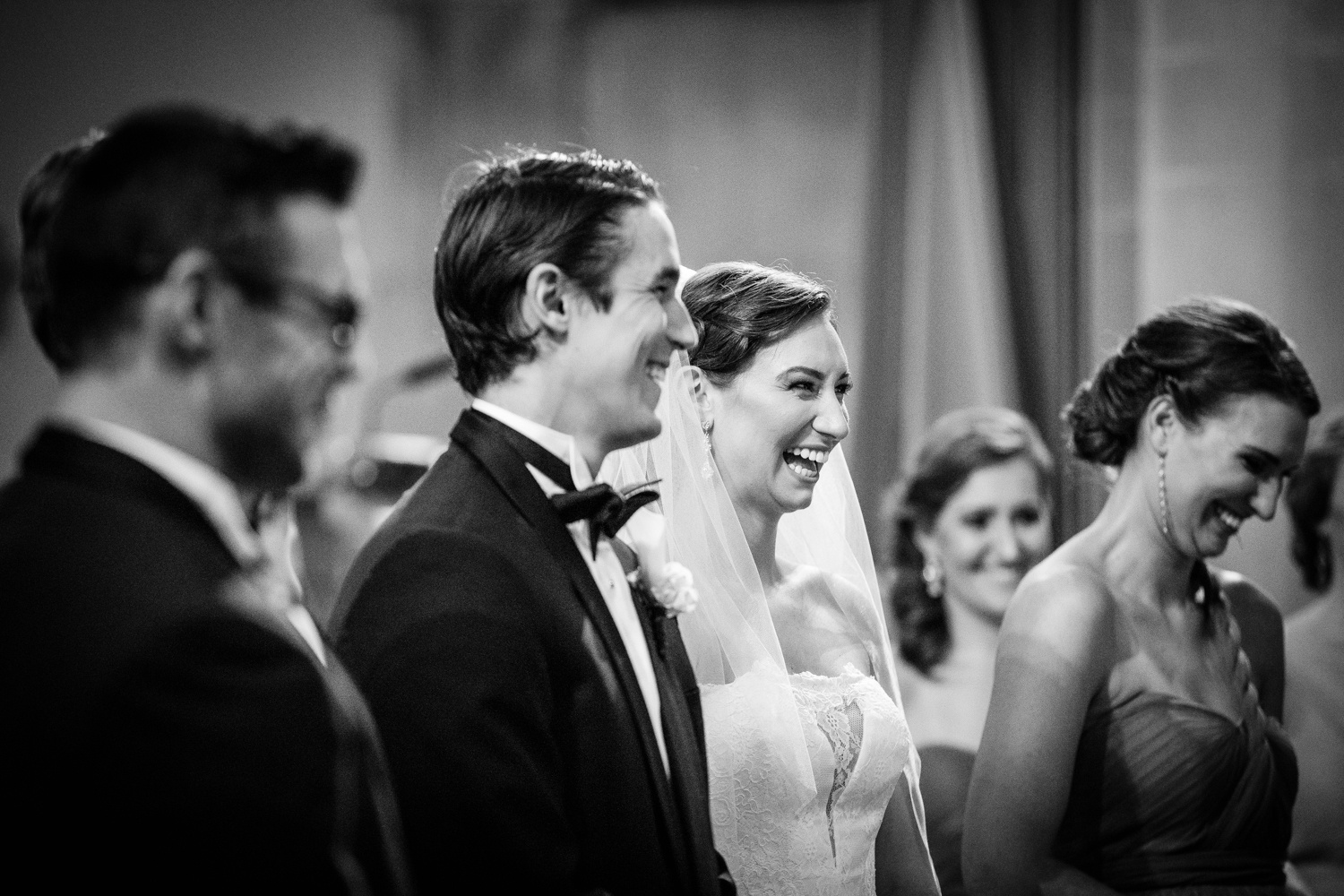 A bride and groom laugh together during a Queen of All Saints Basilica wedding ceremony. 
