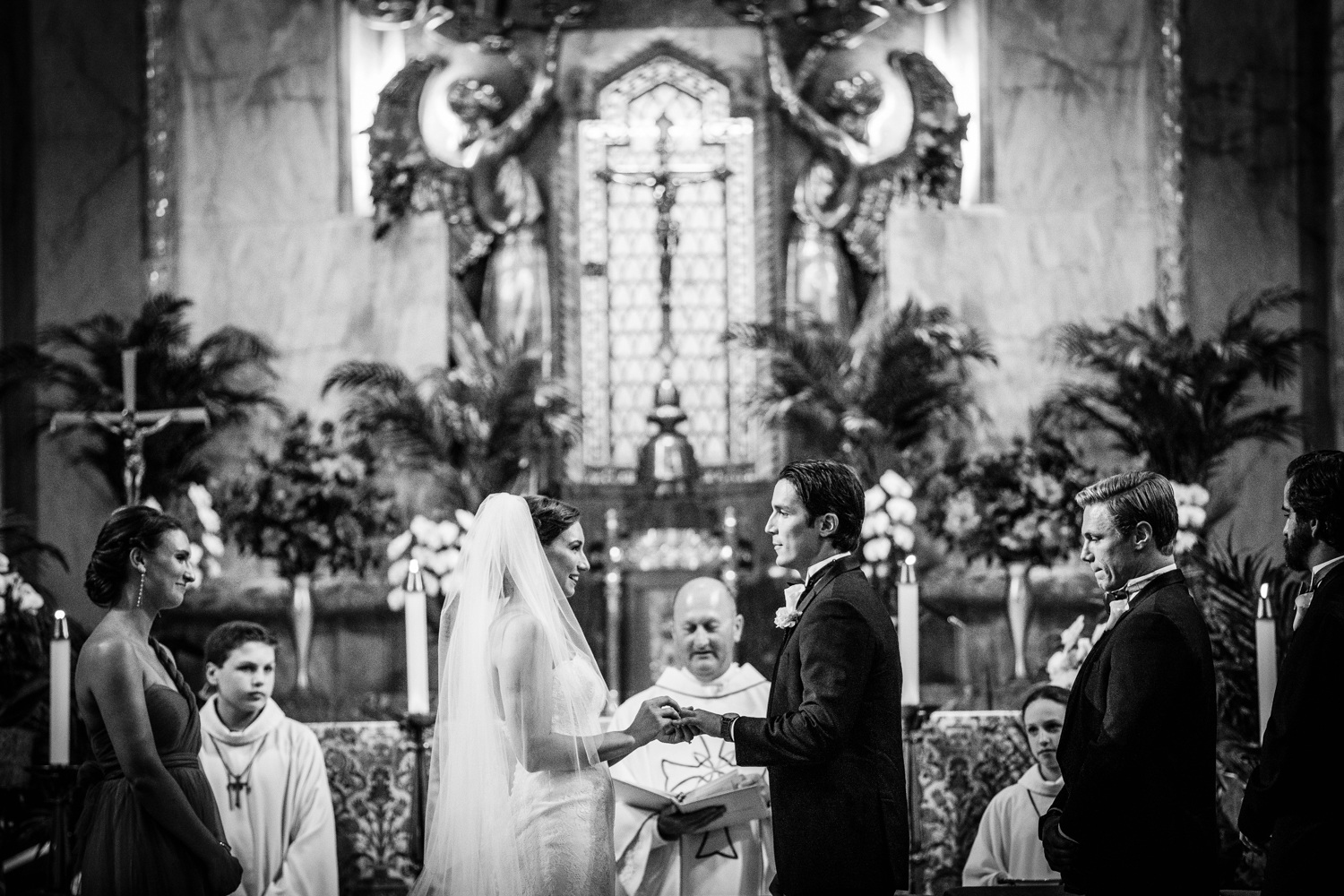 A bride and groom share their wedding rings during a Queen of All Saints Basilica wedding ceremony. 