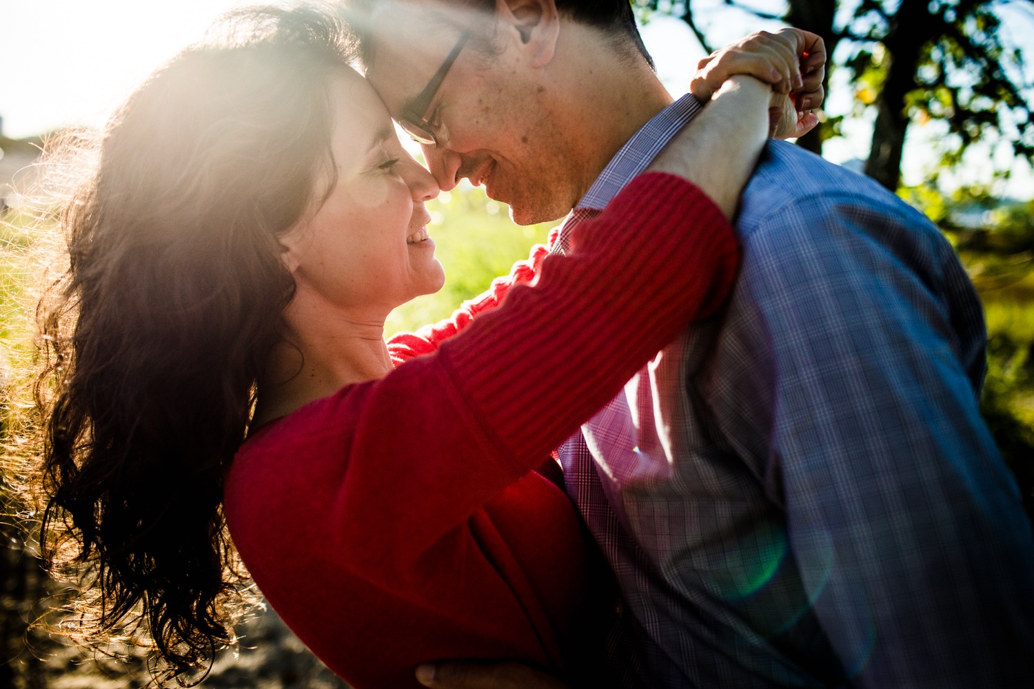 Sunlight flares through the frame as a couple hugs during a Montrose beach engagement session. 