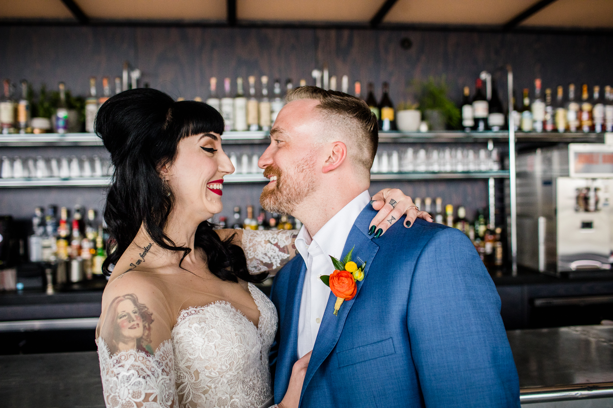 A bride and groom laugh together during a portrait session at the Ace Hotel bar in Chicago. 