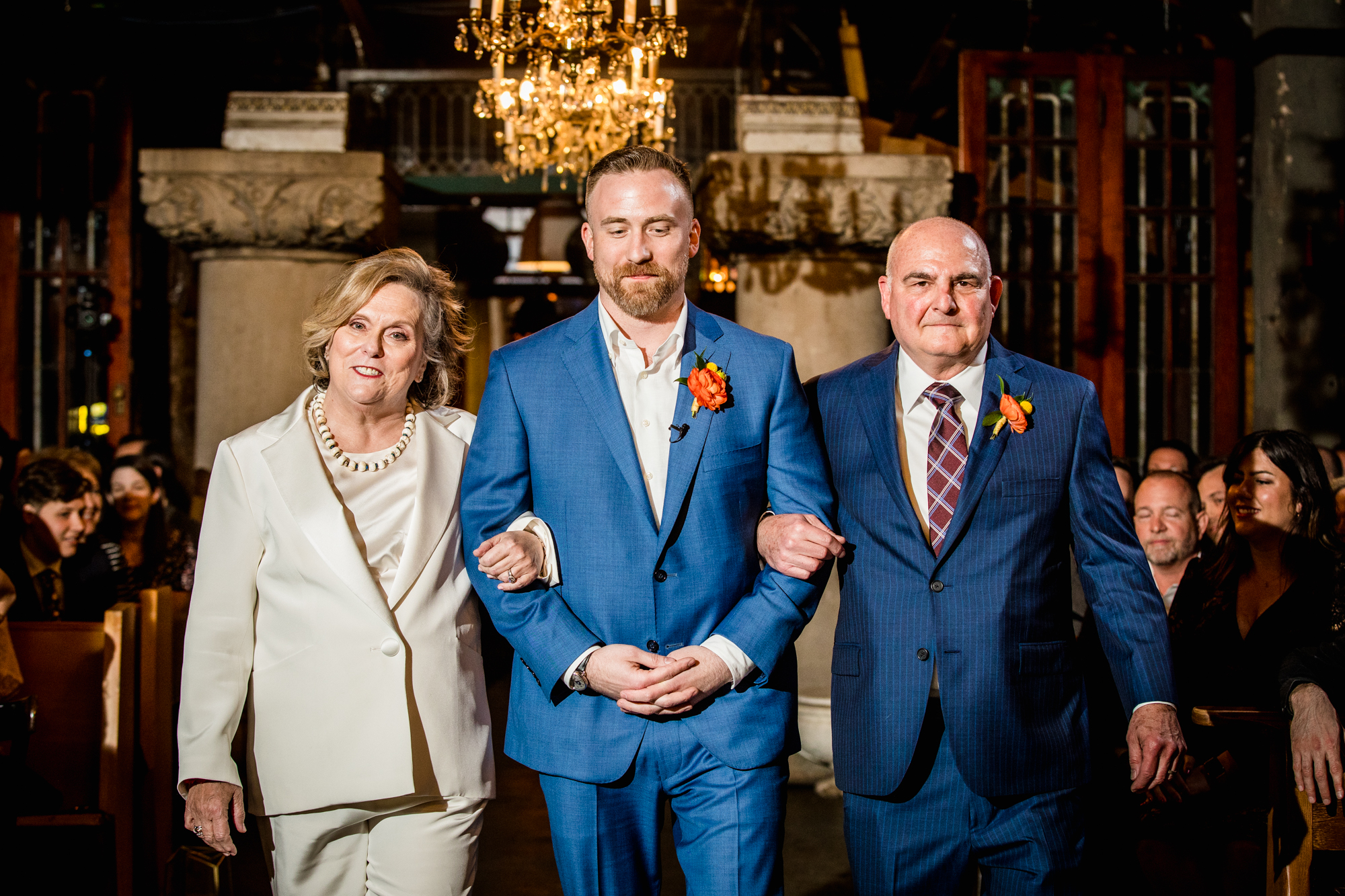 A groom walks down the aisle with his parents during a Salvage One wedding ceremony. 
