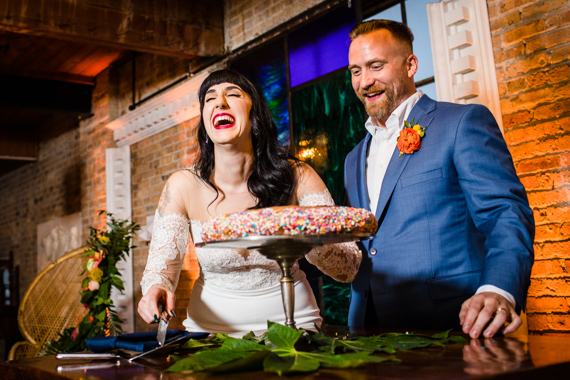 A couple laughs while cutting their donut cake at a Salvage One wedding in Chicago. 