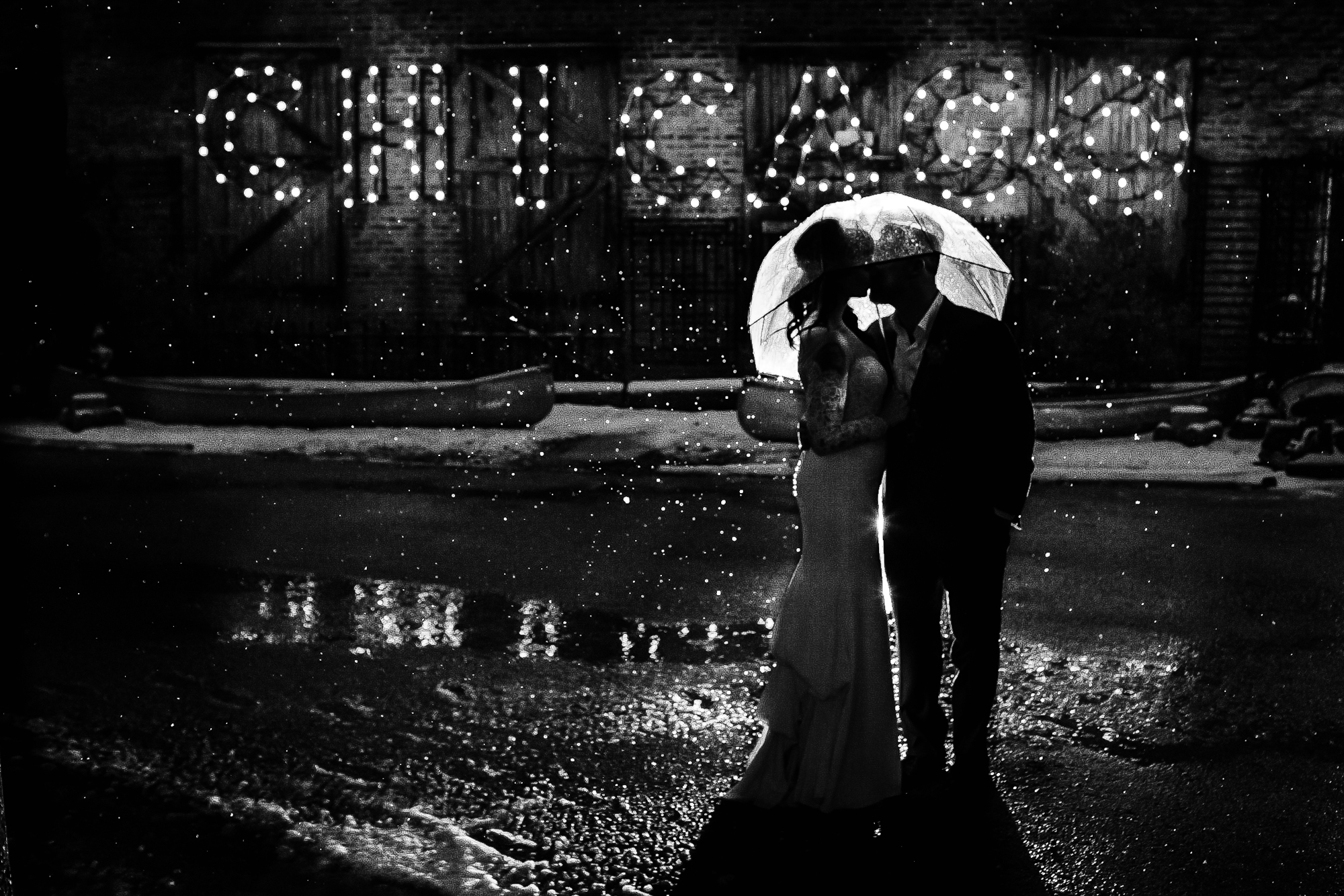 A couple kisses in the rain during a Salvage One wedding in Chicago. 