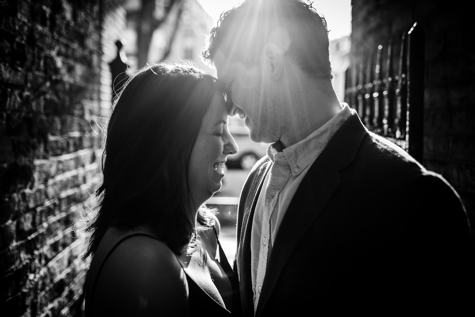 A couple laughs together in a ray of sunlight during a Roscoe Village engagement session. 