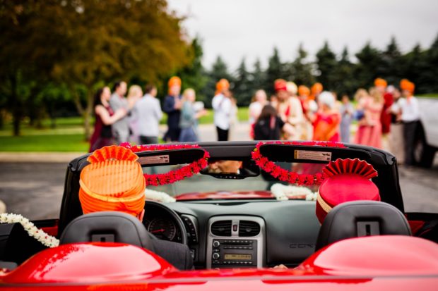 A groom drives in a car for his baraat during an Aurora Balaji Temple wedding