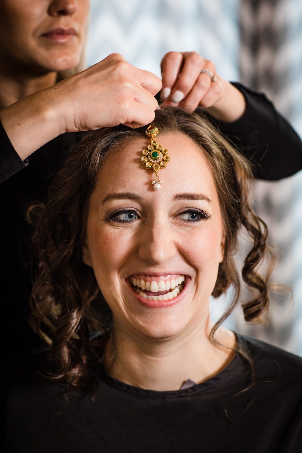 A bride laughs while having her hair done before her Aurora Balaji Temple wedding