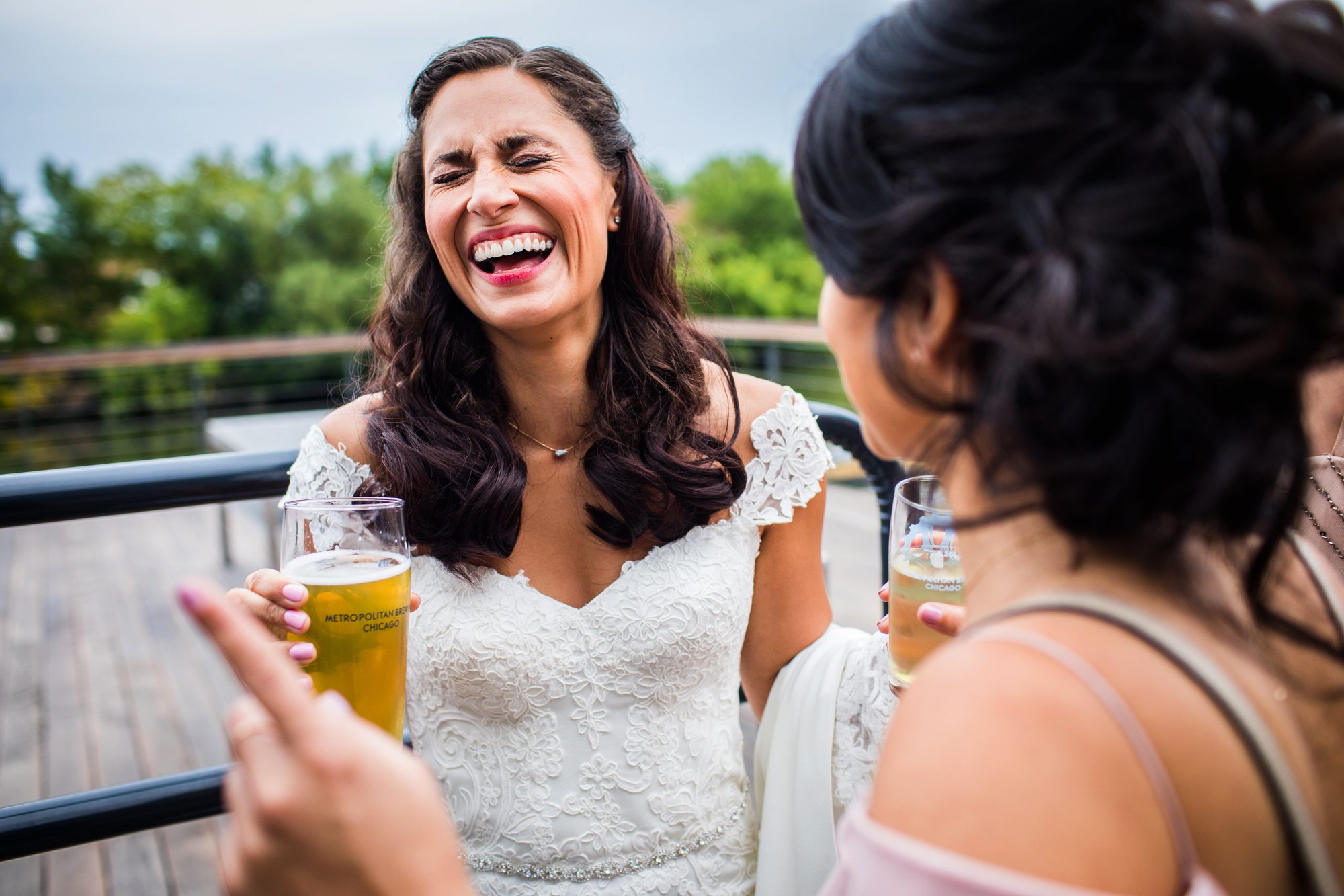 A bride laughs while talking to a friend at Metropolitan Brewing
