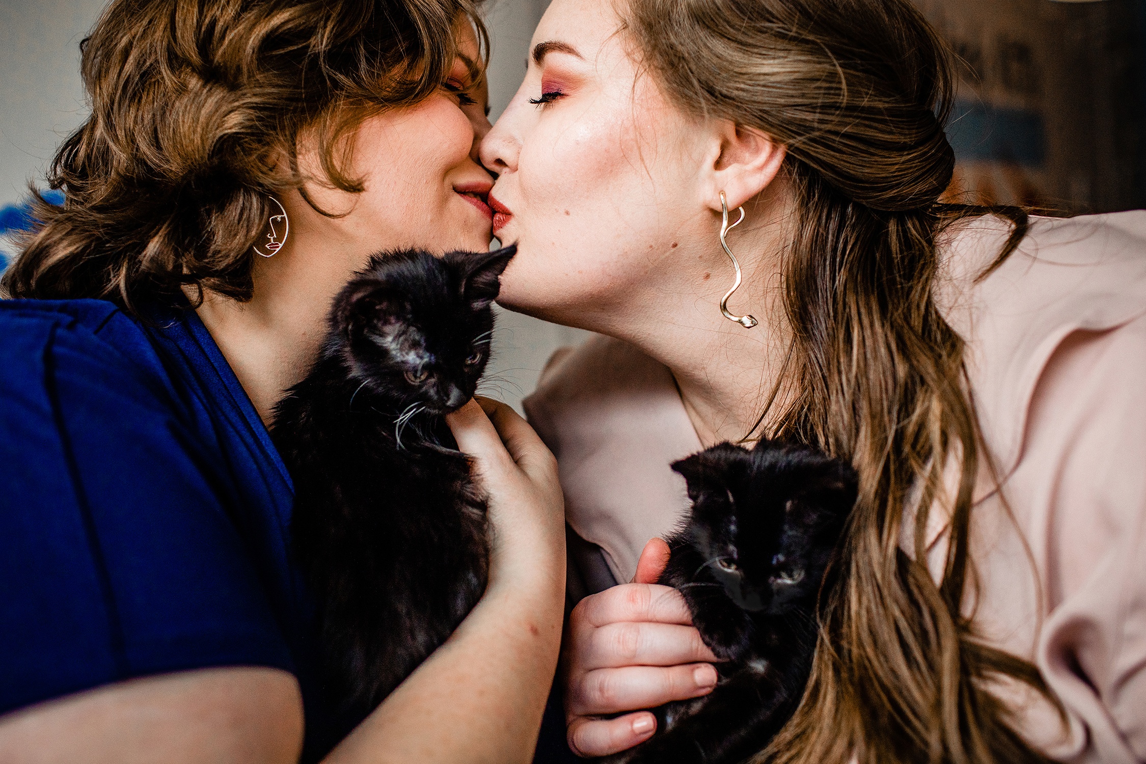 A couple kisses while holding kittens at Windy Kitty Cat Cafe in Chicago.