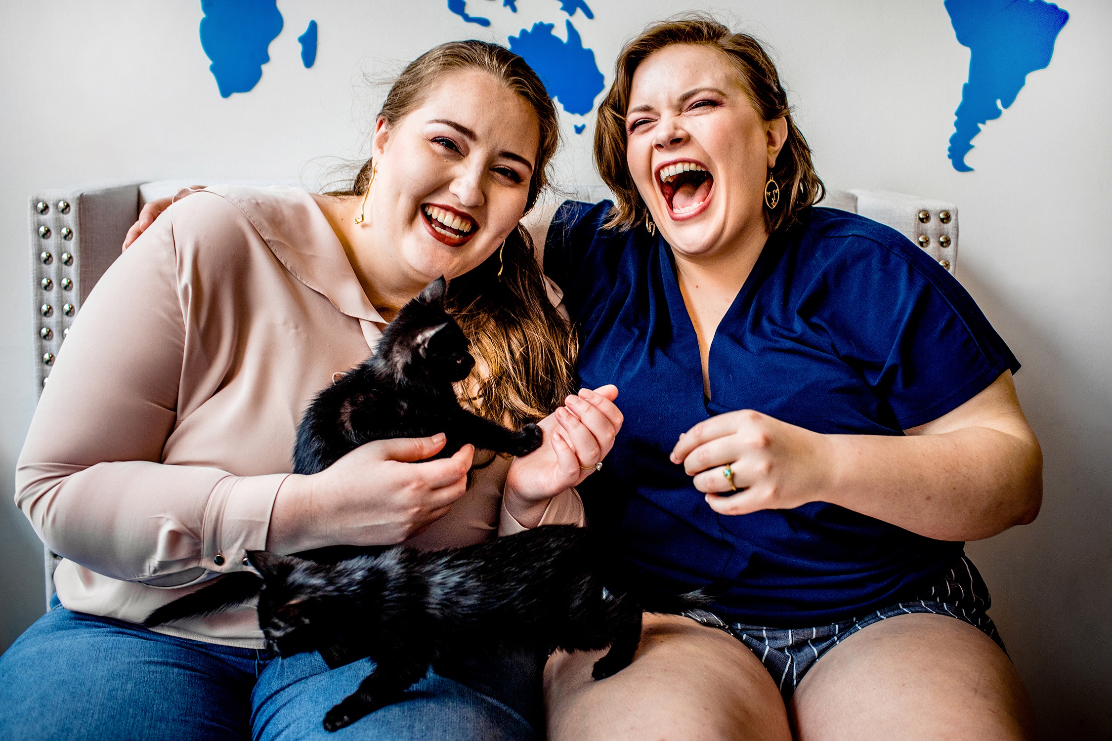 A couple laughs while playing with kittens during a cat cafe engagement session in Chicago.