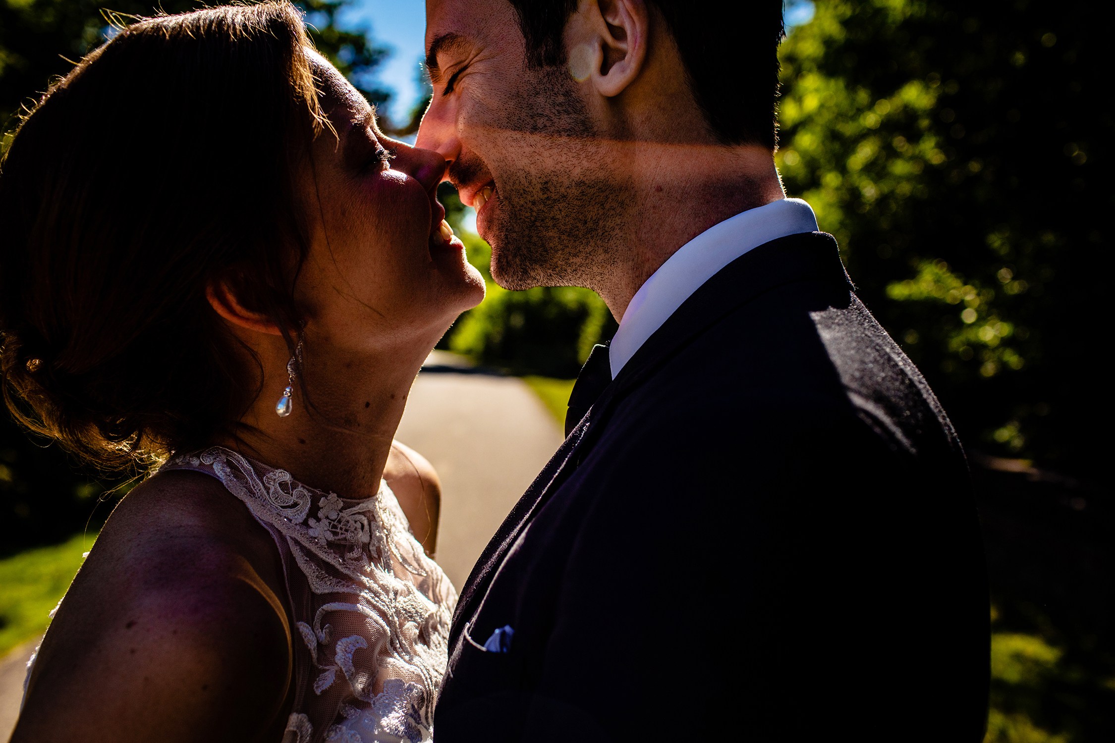 A bride and groom kiss in a ray of sunlight at DuPage River Park in Naperville.