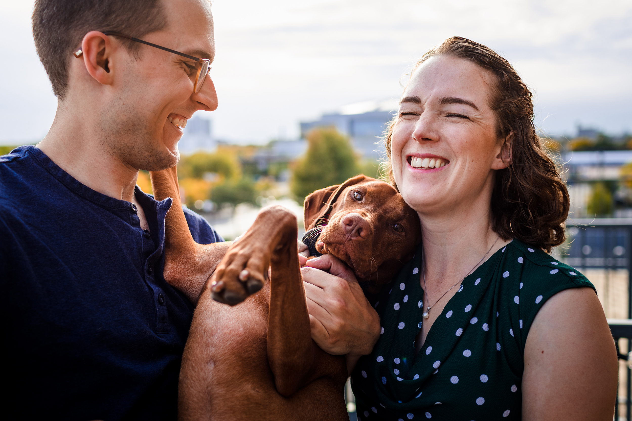 A couple laughs together with their dog during a West Loop engagement session in Chicago.