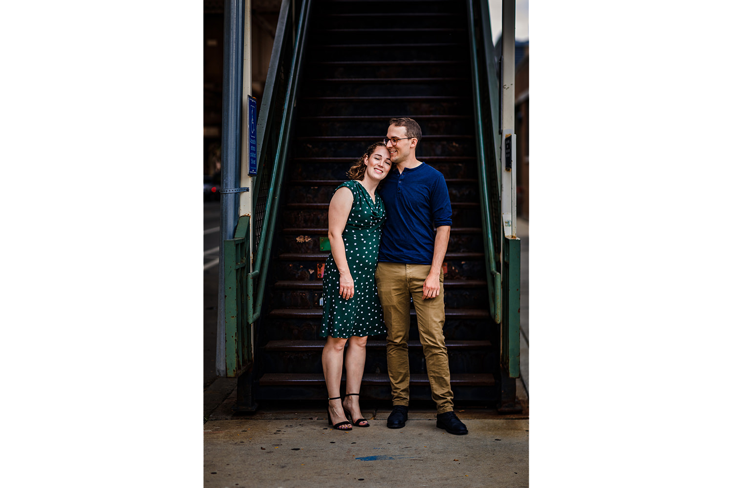 A couple hugs each other on the stairs to the Green Line during an engagement session on Lake Street. 