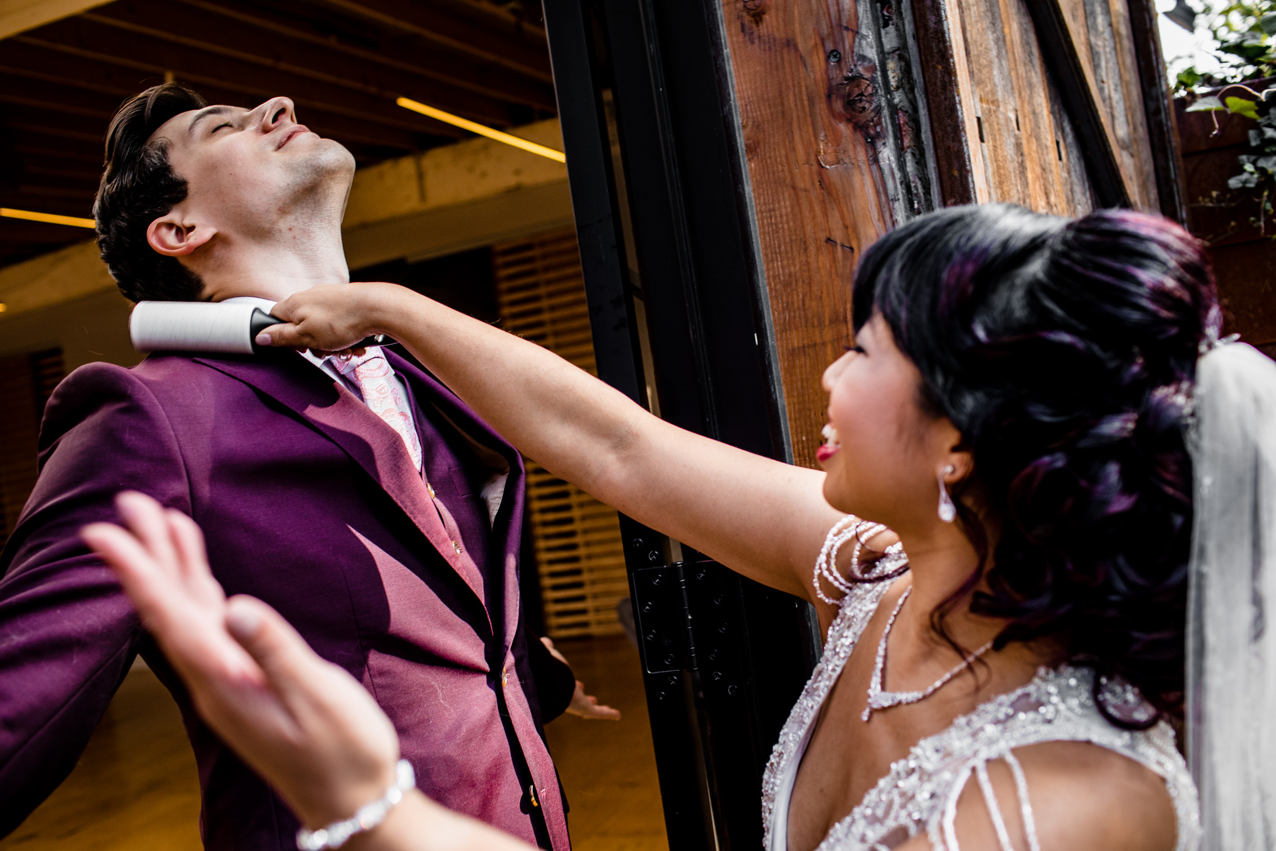 A bride uses a lint roller on her groom during a wedding ceremony at the Joinery.