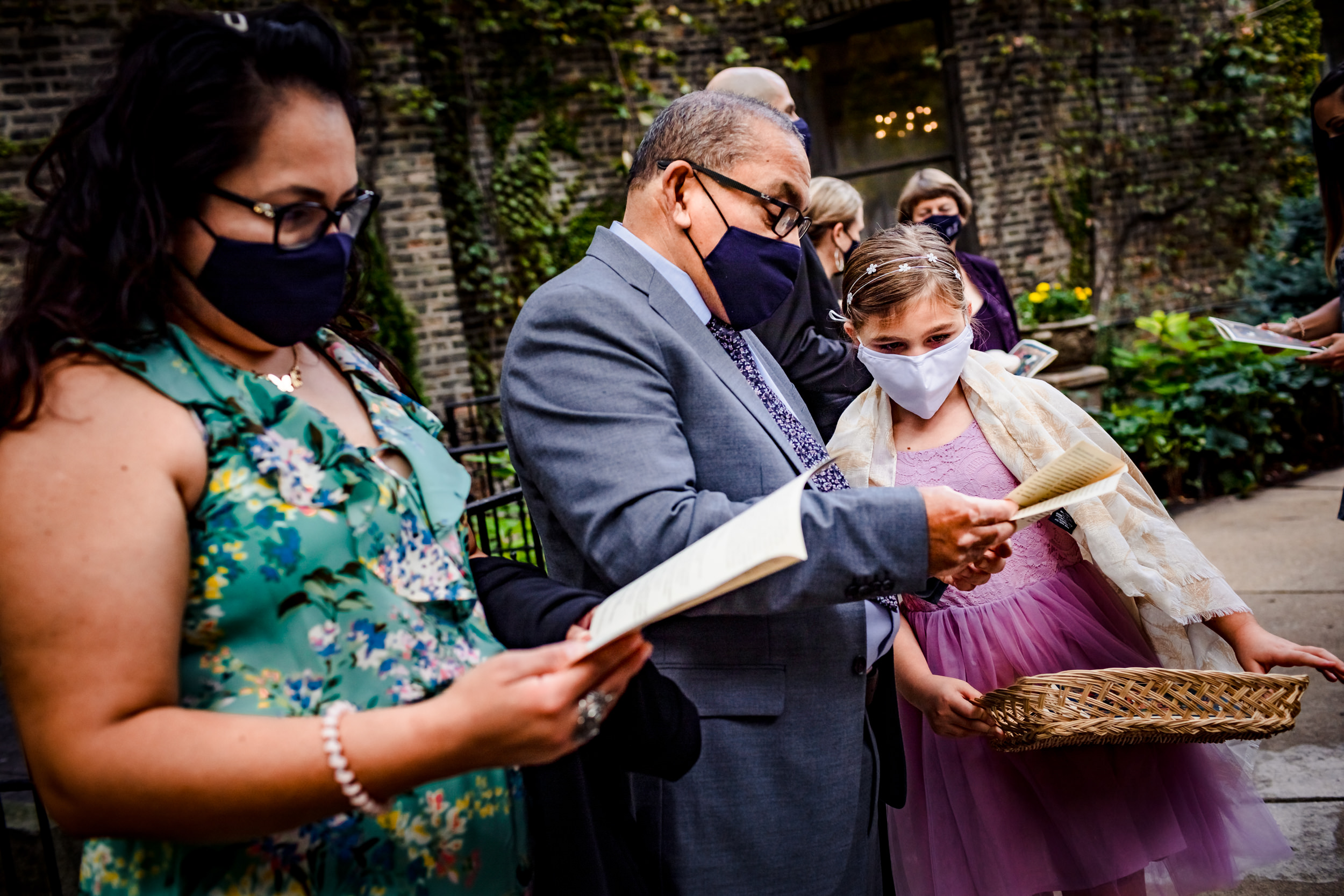 Guests read programs before a wedding ceremony at the Church of the Ascension garden wedding in downtown Chicago.
