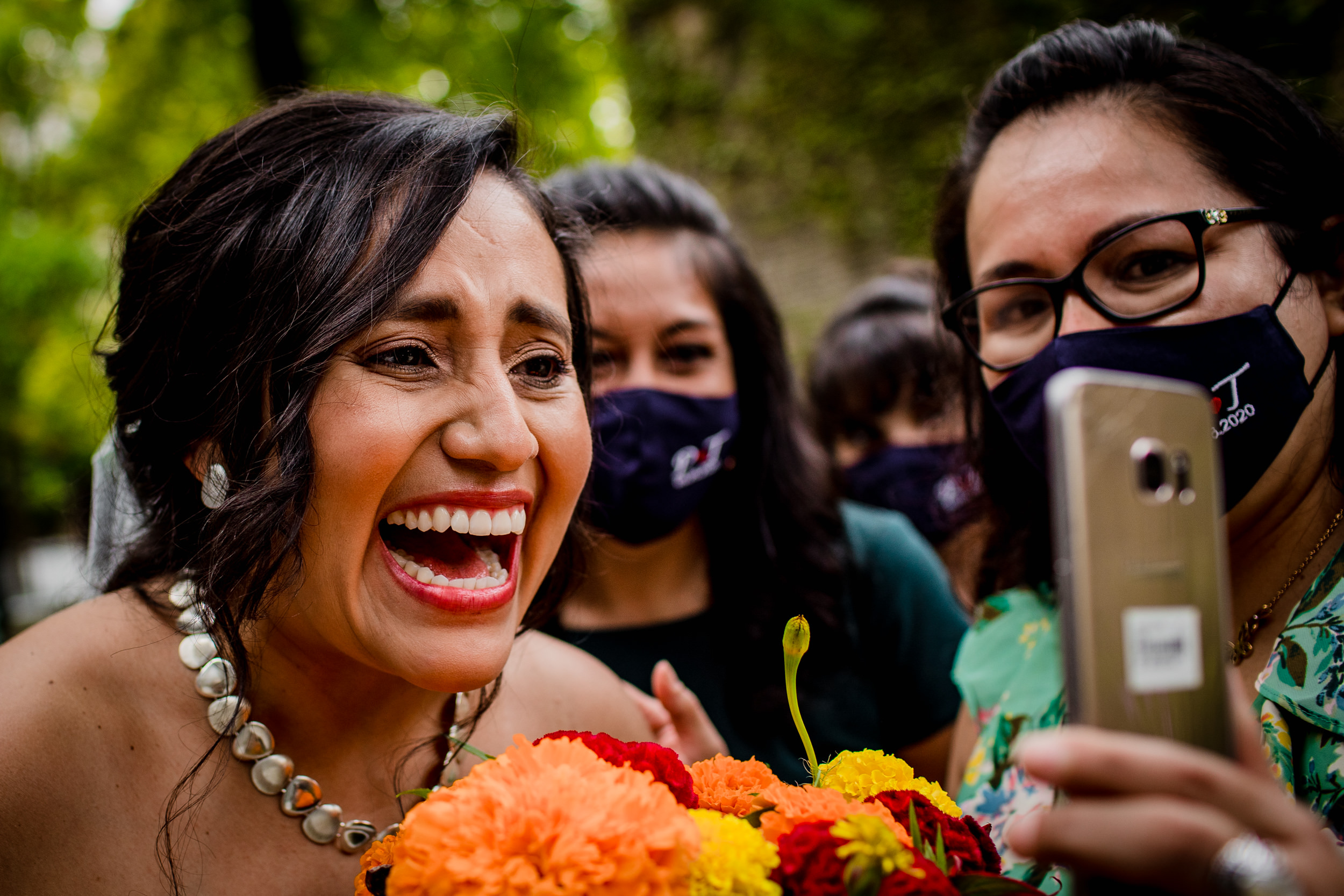 A bride greets family abroad on a phone during a Church of the Ascension garden wedding ceremony in downtown Chicago.