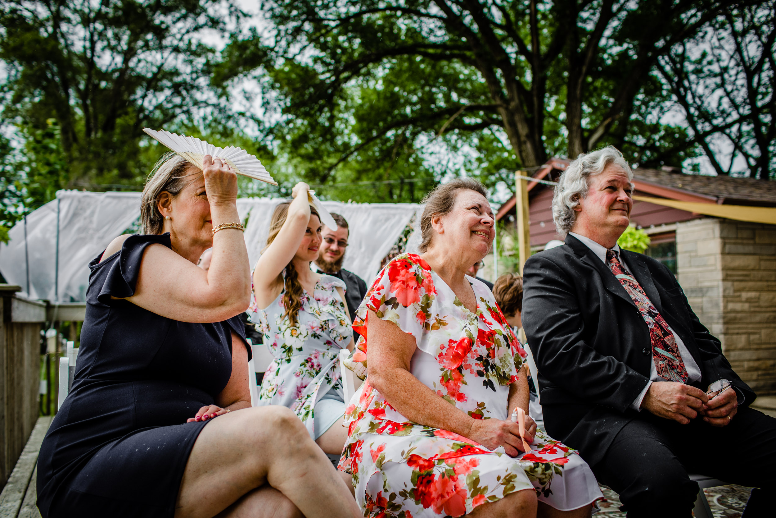Guests listen to a couple share their vows in the rain during a New Lenox backyard wedding.