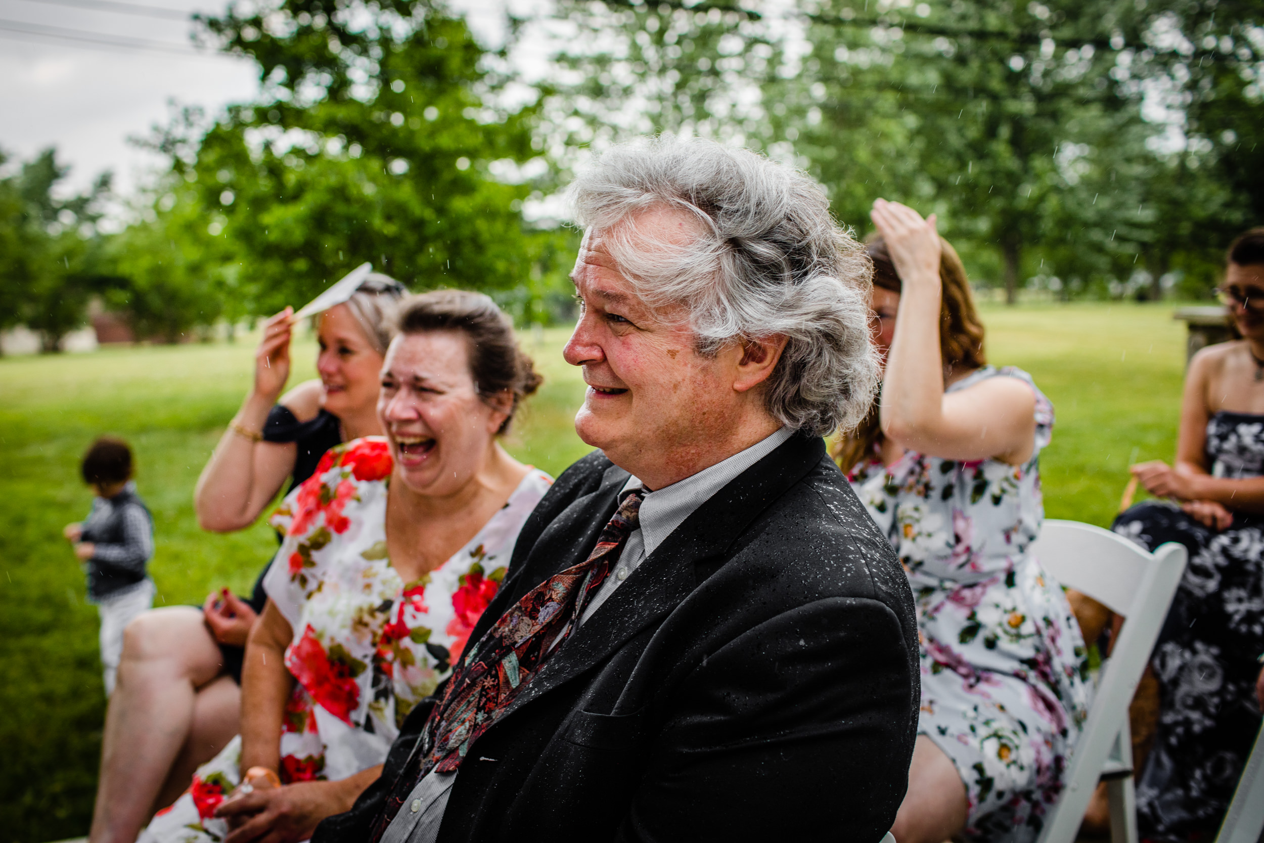 Guests laugh as rain comes down during a backyard wedding in New Lenox, Illinois.