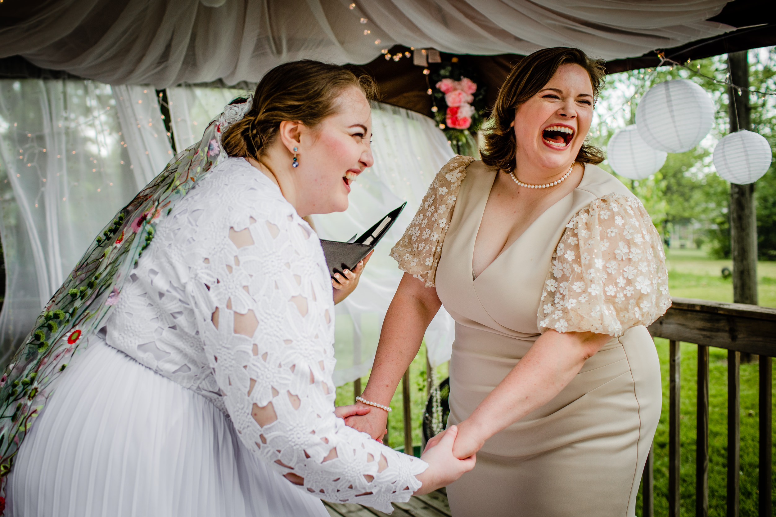 Brides laugh during their New Lenox backyard wedding ceremony.