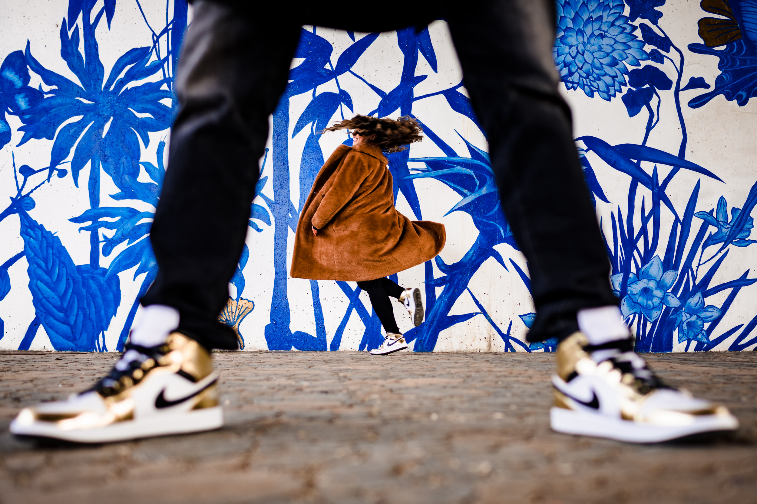 A woman does a spin in sneakers in front of a mural during a Ping Tom Park engagement session. 